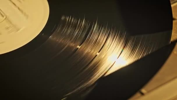 レトロターンテーブルのヴィンテージビニールレコードスピニングクローズアップ ヴィンテージプレーヤーマクロで回転する古いビニールのレコーディング レトロビニル表面を反射するランプの光線 音楽の歴史 ノスタルジック — ストック動画