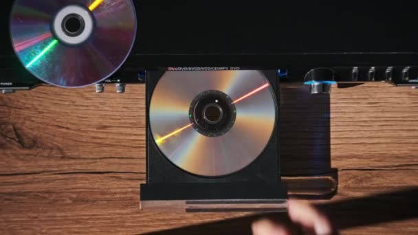 Dvd Cdプレーヤーからコンパクトディスクをアンロードします 男性の手はCdプレーヤーのトレイのクローズアップからCdを排出します レーザー光学情報記憶媒体に記録された音楽 またはデータ エッジングコンパクトディスク — ストック動画