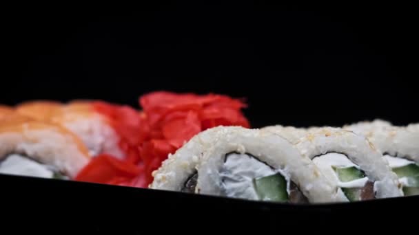 寿司卷在塑料送货箱内旋转特写 寿司盒与新鲜的不同的日本卷 生姜和芥末纺成一个塑料容器 食物运送概念 外卖食物 — 图库视频影像