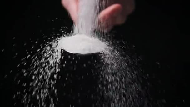 砂糖は黒い背景のスローモーション クローズアップにスプーンに入ります スペースをコピーする 1杯の白砂糖を測定する 砂糖中毒 不健康な食事 太りすぎ 糖尿病 4Kについて — ストック動画