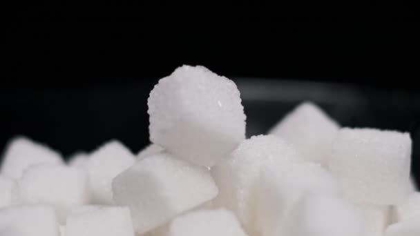 ブラックプレートの砂糖キューブの多くは クローズアップを回転させます 白い精製された砂糖のキューブの山がテーブルの上に回っています 砂糖中毒 不健康な食事 過体重 糖尿病 肥満の概念 コピースペース — ストック動画