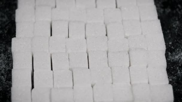 许多糖立方体折叠成正方形 在黑色背景的特写下旋转 白色的精制糖块在旋转 不健康的饮食 糖尿病 复制空间 — 图库视频影像