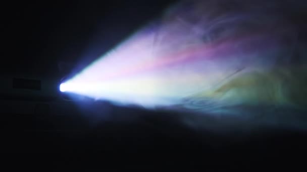 彩色投影仪在黑色背景的烟雾中发出光芒 发光的光束 包裹在一系列的颜色中 光散射光 家庭影院 商业展示 生动的照明效果 探照灯 探照灯 — 图库视频影像