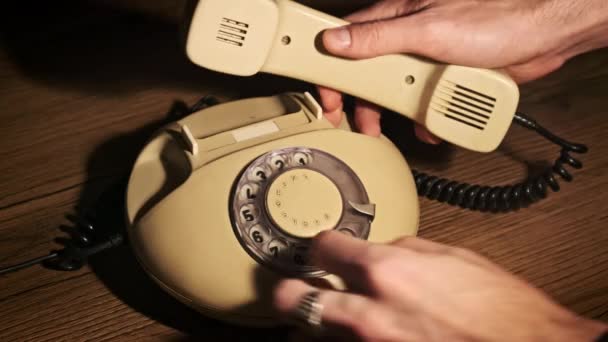 用老旧的转接电话拨打911紧急电话 复古电话 在木制桌子上有一个温暖的灯的手机 带有拨号盘的老式固定电话 男性手指旋转拨号盘4K — 图库视频影像