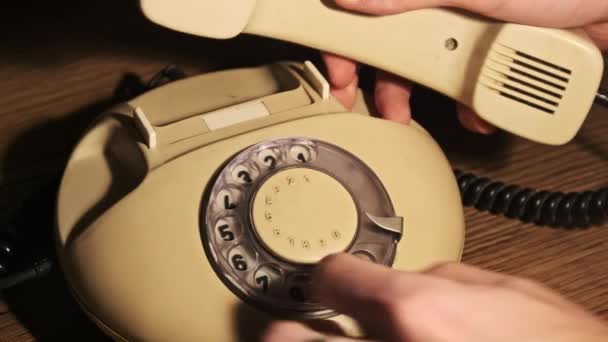 緊急コール 古いロータリー電話で緊急電話番号をダイヤルする ダイヤルディスク付きヴィンテージアナログロータリーランドライン電話 木のテーブルの暖かいライトのハンドセットが付いているレトロな電話 — ストック動画