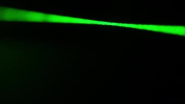 Siyah arka planda yakın plan duman içinde yeşil lazer ışığı. Siste parlayan bir lazer ışını. Karanlığı kesen yoğun, parlak lazer. Bilim kavramı, parti, araştırma.