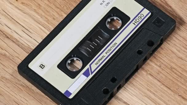 一盒老式盒式磁带躺在一张木制桌子上旋转 古旧录音带在宏中旋转 旧盒式磁带躺在木制表面上 古典音乐过时的音乐80年代90年代怀旧 — 图库视频影像