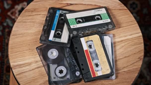 一堆堆不同的盒式磁带在木制桌子上旋转 不同的老式录音带在宏中旋转 旧的录音带躺在木制表面上 古典音乐 — 图库视频影像