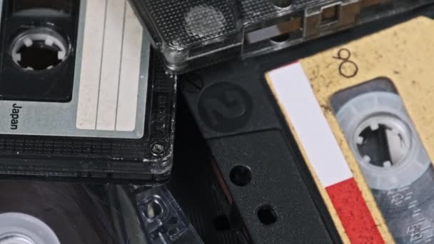 许多不同的盒式磁带堆在一起 在木制桌子上旋转 不同的老式录音带旋转 旧的录音带躺在宏观里 古典音乐复古音乐80年代90年代怀旧 — 图库视频影像