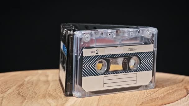 录音带在黑色背景特写的木制桌子上旋转 古旧的录音带旋转宏观 旧盒式磁带躺在木制表面上 古典音乐过时的音乐80年代90年代怀旧 — 图库视频影像