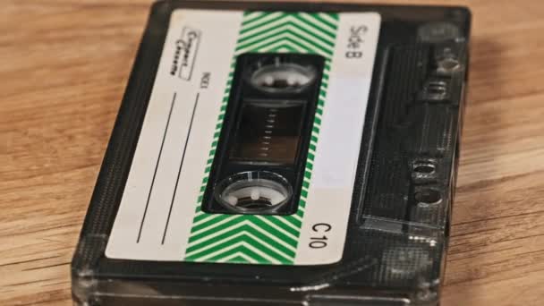 盒式磁带在木制表面上旋转 老式盒式磁带躺在一张木制桌子上 在宏观上旋转着 古典音乐录音带过时的音乐80年代90年代怀旧 — 图库视频影像