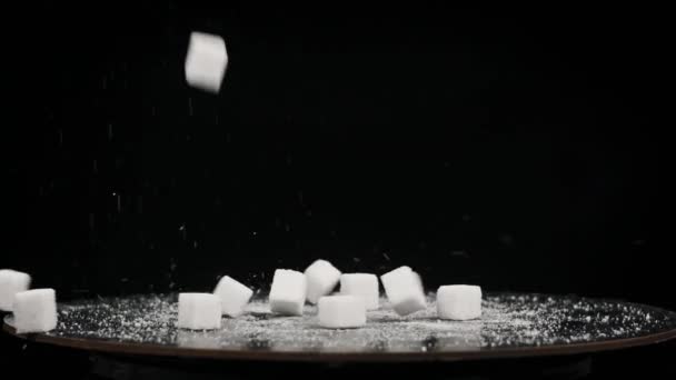 糖立方体以慢动作落在旋转桌子上 靠得很近 坚硬的白糖落在黑色的背景上 不健康的饮食 糖尿病 复制空间 — 图库视频影像