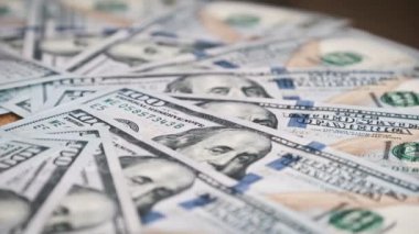 Dolarlar yakın çekimde döner. Yüzlerce Amerikan dolarının yığını yavaşça dönüyor. Çok fazla 100 dolarlık banknot geçmişi var. Konsept finans, para, ödeme, ekonomi, başarı ve bolluk.