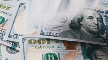 Amerikan doları, yakın plan çekimde dönen bir yığın doların üzerine düşer. Yüzlerce Amerikan doları yavaş yavaş dönüyor. Sayıyorum. Finans, para, ödeme, ekonomi, başarı ve bolluk