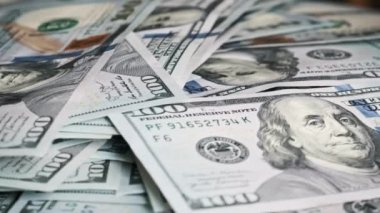 100 dolarlık banknotlar dönen dolar yığınının üzerine düşüyor. Yüzlerce Amerikan dolarının yığını yavaşça dönüyor. Finans, para, ödeme, ekonomi, başarı ve bolluk.