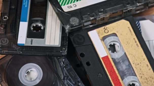 一堆堆不同的盒式磁带在木制桌子上旋转 不同的老式录音带在宏中旋转 旧的录音带躺在木制表面上 古典音乐 — 图库视频影像