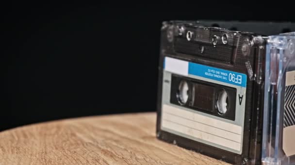 录音带在黑色背景特写的木制桌子上旋转 古旧的录音带旋转宏观 旧盒式磁带躺在木制表面上 古典音乐过时的音乐80年代90年代怀旧 — 图库视频影像