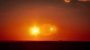 Saf turuncu gökyüzünde parıldayan mercekli muhteşem günbatımı zamanı. Ufuktan batan parlak güneş. Efsanevi, canlı bir renk. Zaman aşımı. Güzel gün batımı. 4K