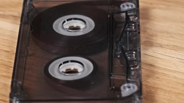 투명한 오디오 카세트는 테이블 클로즈업에 놓이고 회전합니다 빈티지 오디오 테이프 — 비디오