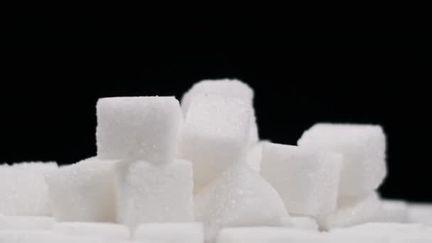 成堆的糖块在黑色背景的特写下旋转 许多白色精致的糖块在桌子上旋转着 概念糖瘾 不健康的饮食 糖尿病 复制空间 — 图库视频影像