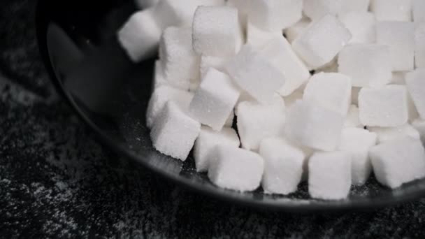 ブラックプレートの砂糖キューブの山は クローズアップを回転します 多くの白い精製された砂糖キューブがテーブルの上に回っています 砂糖中毒 不健康な食事 過体重 糖尿病 肥満の概念 コピースペース — ストック動画