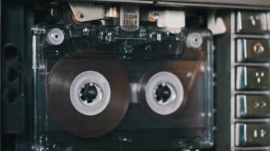 Ses kayıt cihazı oynatıcısı. Eski şeffaf bir ses kasetini yakından dinleteceğim. Bir retro çalgıcıda klasik plak sesi. Bant makaraları güvertede döner. Konuşmaların kaydı, aramalar, arşiv, 80 'ler.