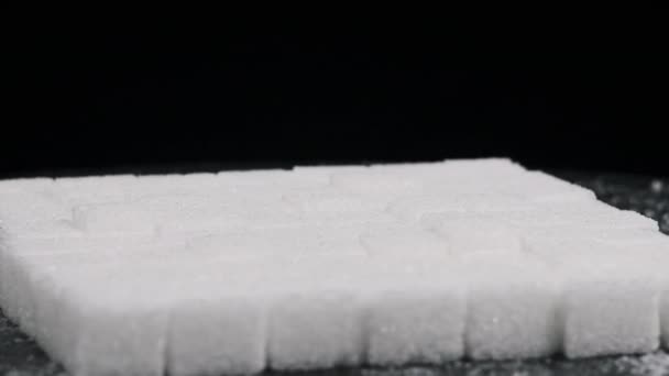 许多糖立方体折叠成正方形 在黑色背景的特写下旋转 白色的精制糖块在旋转 不健康的饮食 糖尿病 复制空间 — 图库视频影像