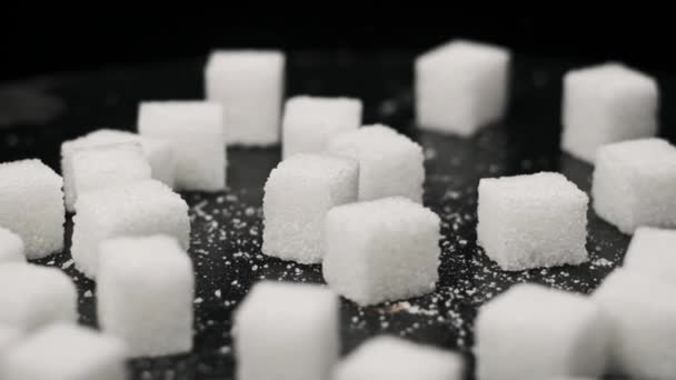 糖立方体以慢动作落在旋转桌子上 靠得很近 硬的白糖落在黑桌上 不健康的饮食 糖尿病 复制空间 — 图库视频影像