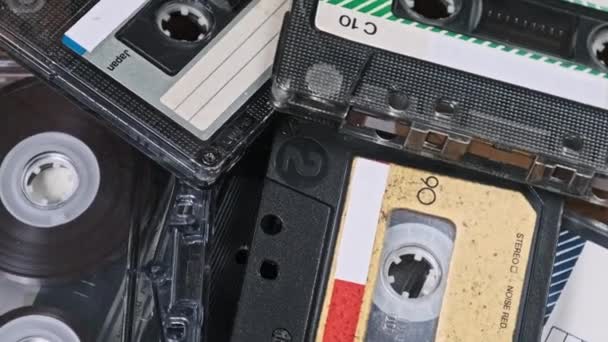 许多不同的盒式磁带堆在一起 在木制桌子上旋转 不同的老式录音带旋转 旧的录音带躺在宏观里 古典音乐复古音乐80年代90年代怀旧 — 图库视频影像