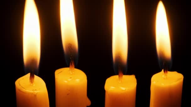 四支蜡烛在黑色的背景上燃烧和熄灭 复制空间 蜡烛的火焰点燃了特写 炽热的烛焰 孤立无援概念纪念 记忆等 — 图库视频影像