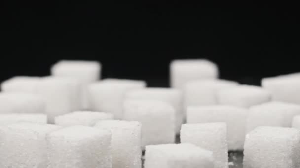 糖立方体旋转在桌子上的特写 大量的白糖在黑色的背景上光滑地旋转着 概念糖瘾 不健康的饮食 糖尿病和肥胖 复制空间 — 图库视频影像