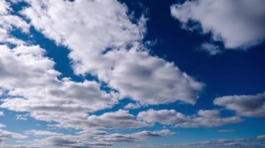 Kümülüs bulutlarının zamanı mavi gökyüzünde ilerliyor. Işık ve ağır sakin bulutların arka planı bulutlu uzayda şekil değiştirir. Doğal arka plan, hızlandırılmış zaman, kopyalama alanı. 4K.
