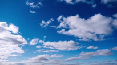 Kümülüs bulutlarının zamanı mavi gökyüzünde ilerliyor. Işık ve ağır sakin bulutların arka planı bulutlu uzayda şekil değiştirir. Doğal arka plan, hızlandırılmış zaman, kopyalama alanı. 4K.