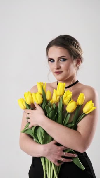 Mujer Joven Traje Negro Tiernamente Abraza Gran Ramo Tulipanes Amarillos — Vídeo de stock