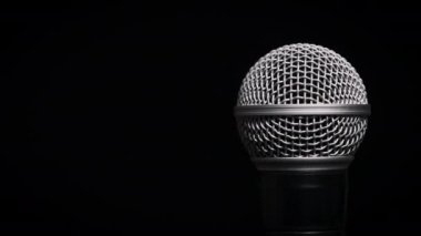 Ses mikrofonu yavaşça siyah bir arkaplanda döner. Dinamik yüzeyde yakın çekim krom ızgarası. Kopyalama. Konsept kayıt stüdyosu, ses, podcast, karaoke, sesli kitap.