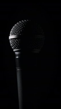 Ses mikrofonu siyah arka planda yavaşça arka planda döner. Dinamik olarak yakın plan krom ızgarası. Kopyalama. Konsept kayıt stüdyosu, ses, podcast, karaoke, sesli kitap. Dikey
