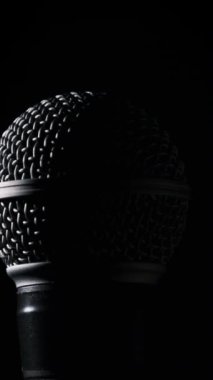Dinamik mikrofon arka planda yavaşça döner. Ses mikrofonunda yakın çekim krom ızgarası. Kopyalama. Konsept kayıt stüdyosu, ses, podcast, karaoke, sesli kitap. Dikey video