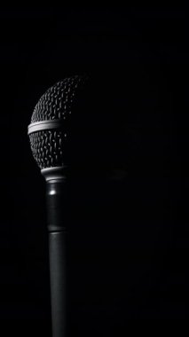 Ses mikrofonu siyah arka planda yavaşça arka planda döner. Dinamik olarak yakın plan krom ızgarası. Kopyalama. Konsept kayıt stüdyosu, ses, podcast, karaoke, sesli kitap. Dikey