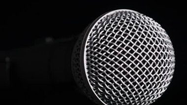 Ses mikrofonu siyah bir arka planda yavaşça döner. Dinamik yüzeydeki krom ızgara yavaşça dönüyor. Konsept kayıt stüdyosu, ses, podcast, karaoke, sesli kitap. Boşluğu kopyala