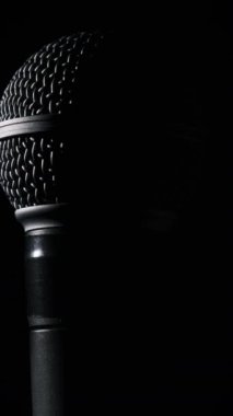Dinamik mikrofon arka planda yavaşça döner. Ses mikrofonunda yakın çekim krom ızgarası. Kopyalama. Konsept kayıt stüdyosu, ses, podcast, karaoke, sesli kitap. Dikey video
