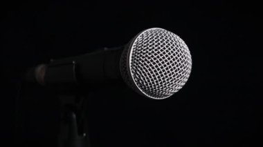 Ses mikrofonu siyah bir arka planda yavaşça döner. Dinamik yüzeydeki krom ızgara yavaşça dönüyor. Konsept kayıt stüdyosu, ses, podcast, karaoke, sesli kitap. Boşluğu kopyala