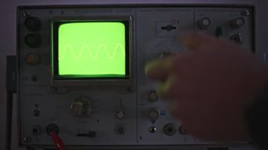 Eski bir osiloskopun makro görüntüsü. CRT ızgarada parlak yeşil bir dalga formu gösteriyor. Bu resim radyo sinyal analizi ve ölçümlerinde kullanılan araçları vurgular.