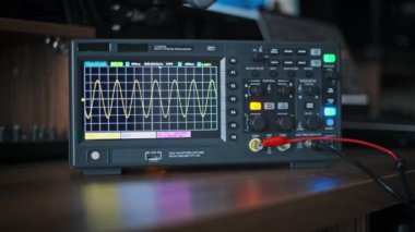 Osiloskop sabit bir sinüs dalgası sinyali gösterir. Elektronik prensipleri ve sinyal analizini resmetmek için ideal olan yakın çekim ekrana odaklandı.