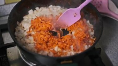 Doğranmış soğan ve rendelenmiş havuç bir tavada cızırdar ve lezzetli bir yemek için güzel kokulu ve renkli bir taban oluşturur. Bir spatula usulca sebzeleri karıştırır, yemek pişirmeyi bile garantiler..
