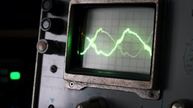 Eski bir osiloskop ekranının yakın plan görüntüsü, dinamik ve değişken yeşil dalga formları gösteriyor. Bilimsel analiz veya geçmişe dönük teknolojiyi vurgulayan projeler için ideal.