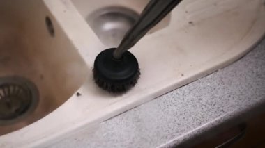 Buharlı temizleyicinin yakın plan bir fırça ekiyle mutfak lavabosunun kenarını titizlikle temizlerken, kiri temizlerken ve hijyeni sağlarken..