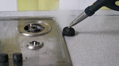 Yakın çekim, mutfak tezgahını titizlikle temizlemek için kullanılan yuvarlak fırçalı bir buhar temizleyiciyi gösteriyor. Buhar kiri ve kiri etkili bir şekilde eritiyor ve lekesiz bir son ortaya çıkıyor.