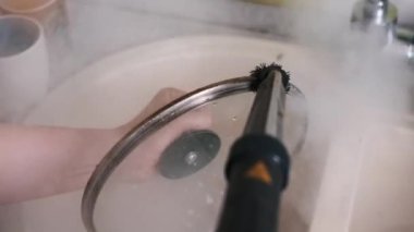Buharlı temizleyicinin detaylı yavaş çekimleri, bir fırça eklentisiyle, kir tabakasının kapaktan titizlikle kaldırılması, buhar temizliğinin etkinliğini vurguluyor..