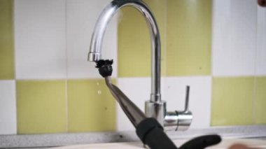 Buharlı temizleyicinin yakın plan fırça eklentisiyle mutfak musluğunu titizlikle temizlemek ve dezenfekte etmek, kiri ve kireç pulunu temizlemek..