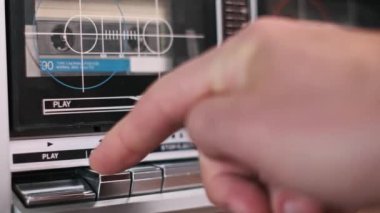 Bir elin, klasik bir teybin çalma tuşuna basıp kaseti aktifleştirmesi ve müziği başlatması..